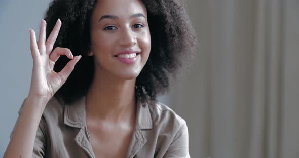 Close Up Happy Mixed Race Girl Looking at Camera with Wide Toothy Smile, Raises Hand in Front of Her