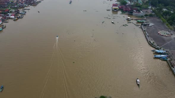 Motor boat speeding on Musi river in city of Palembang, aerial drone view