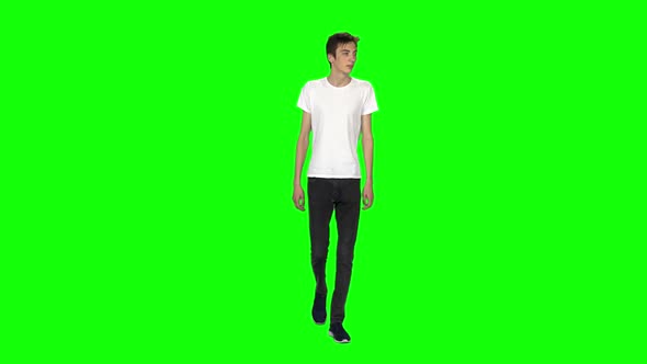 Tall Skinny Teen Guy Calmly Walking on Green Screen Background. Chroma Key. Front View. Slow Motion