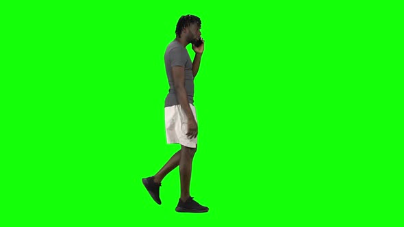African American Man Walking and Talking on the Mobile Phone at Green Screen, Chroma Key. Profile
