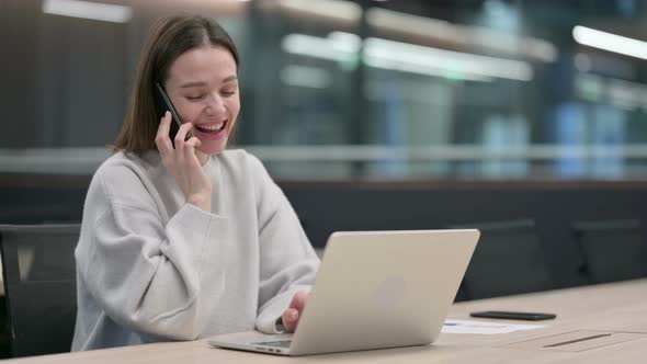 Woman Talking on Phone while using Laptop