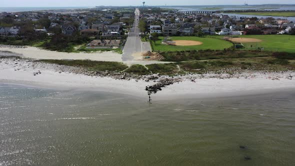 An aerial view over the waters, facing an empty beach on a bright & sunny day in the summer. The dro