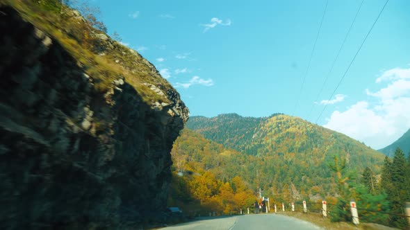 camera shoots from first person, car is driving along a narrow mountain road.