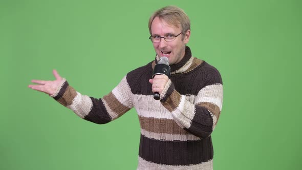 Studio Shot of Happy Handsome Man Presenting Something with Microphone