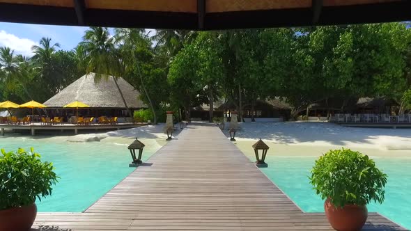 View of a tropical island dock pier over a beach.