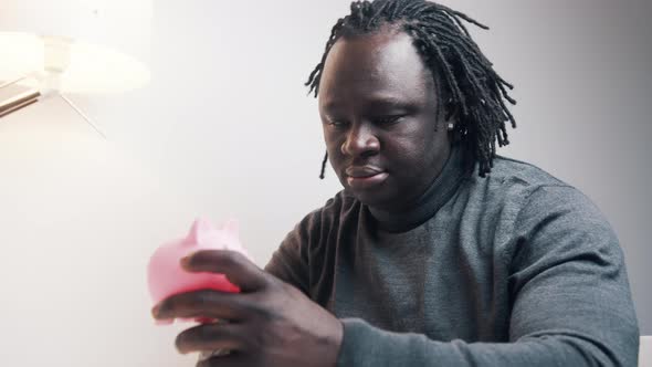 Depresed African American Black Man Holding Empty Piggy Bank