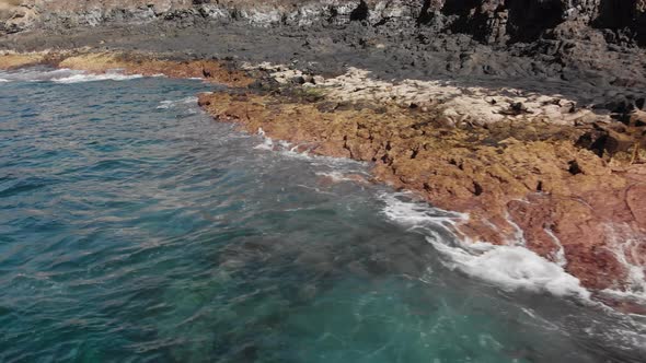 Aerial Shot. Flying Along the Volcanic Shore. The Landscape Is Big Stones of Yellow and Brown Color