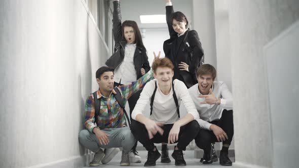 Wide Shot of Carefree Caucasian High School Students Posing in School Corridor