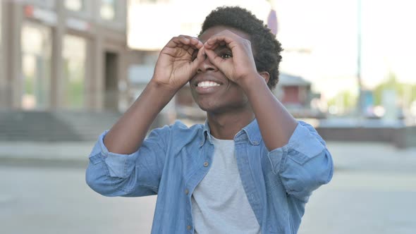 Outdoor Young African Man Searching with Handmade Binocular