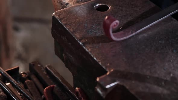 Blacksmith Bends an Oblong Heated Metal Detail By Hitting in with a Hammer on Anvil