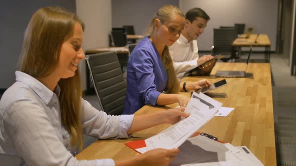 Young Businesswomen Reading Some Docs Sitting at Work Desk.