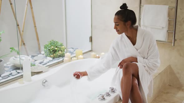 Mixed race woman sitting by a bathtub at home