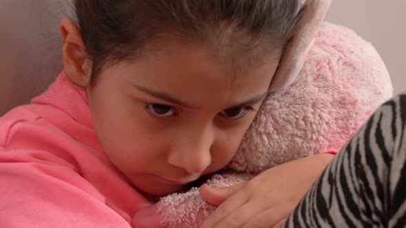 Unhappy kid hugging her toy.