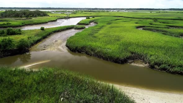 An aerial flyover of a stream creek river leading through a marsh to the Matanzas River in St. Augus