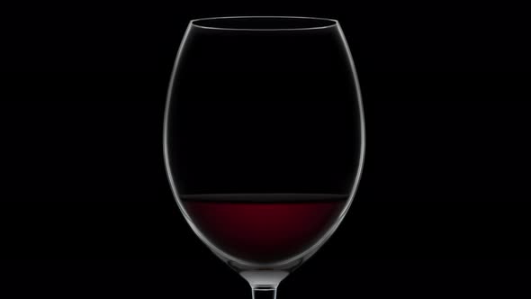 Empty Goblet Fills Up with Dessert Wine on Black Background