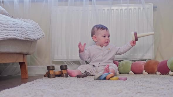 A happy child is playing with a pyramid on the carpet in the nursery. Toddler baby boy is playing