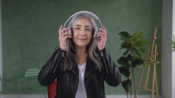  Stylish Retired Woman which Putting on Headphones and Looking at Camera with Lovely Smile