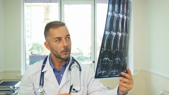 A Thoughtful Doctor Carefully Examines an X-Ray Shot