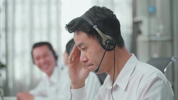 A Man Of Three Asian Call Centre Agents Headache Because His Colleagues Are Talking With Each Other