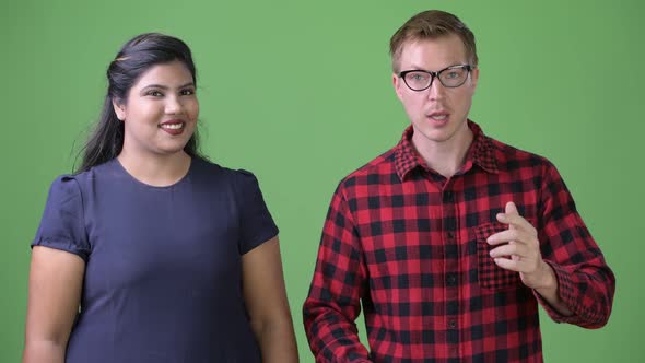 Young Multi-ethnic Business Couple Together Against Green Background