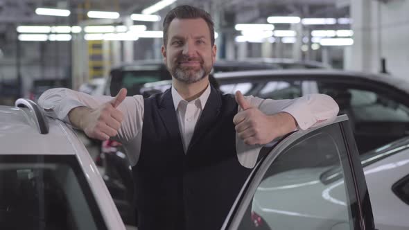 Portrait of Handsome Caucasian Businessman Standing Next To Open Car with Thumbs Up. Smiling Adult