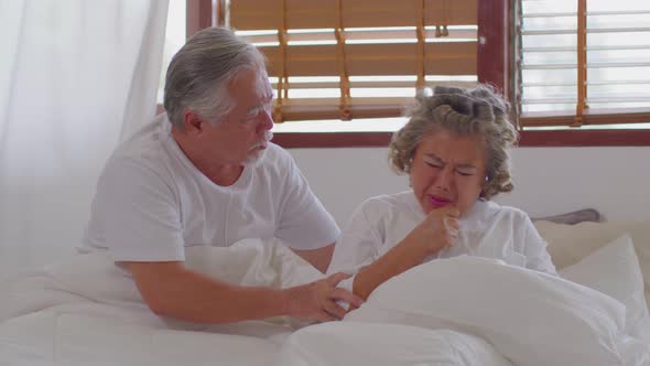 Asian Elderly woman sneezing and coughing sit on bed and hasband take care beside with love at home