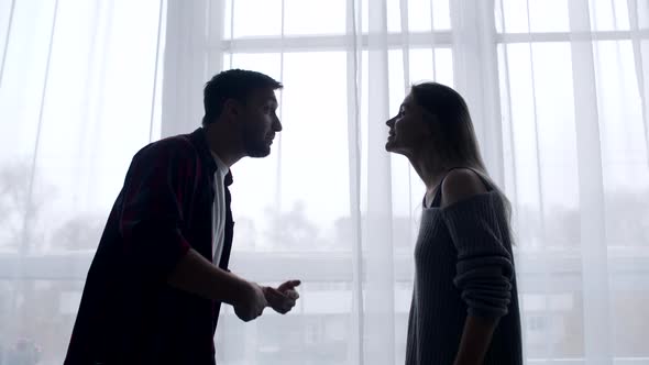 Married Couple Swears in Living Room Background of Curtains and Windows Husband Insults Wife By