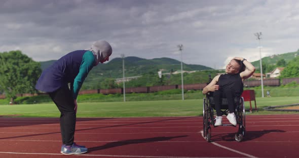 A Female Person with Disabilities Warming Up on Wheelchair at Athletics Training Track with Muslim