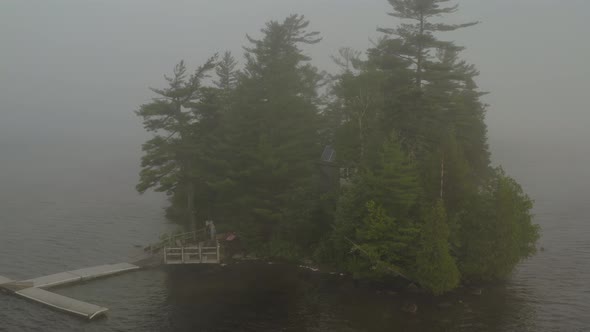 Thick fog surround island on Moosehead lake orbiting aerial