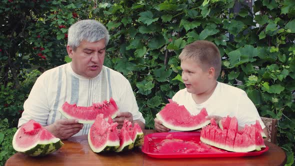 Dad and Son Enjoy Eating Slices of Ripe Watermelon Appetizingly