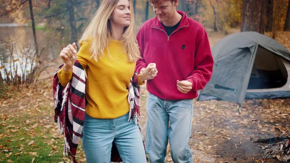 Young Pair Smiling and Dancing in Autumn Wood Near River