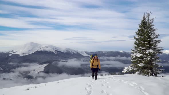A Man with a Backpack Travels in the Mountains in Winter