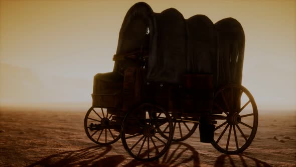 Canvas Covered Retro Wagon in Desert at Sunset