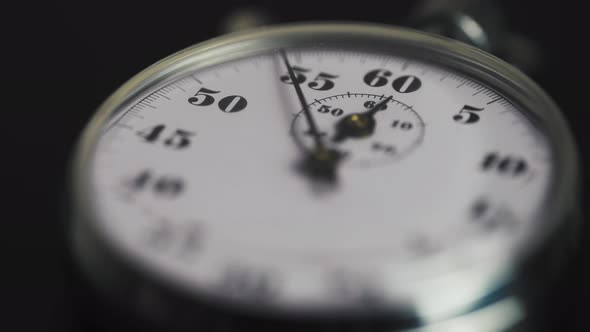 Macro shot of a classic metallic retro mechanical analog stopwatch against a dark background