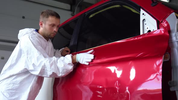 Worker Man Is Stroking Dye on Car Body By Hand in Glove in Auto Service