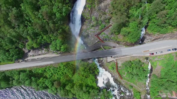 Massive Svandalsfossen waterfall creating rainbow on road bridge in Norway