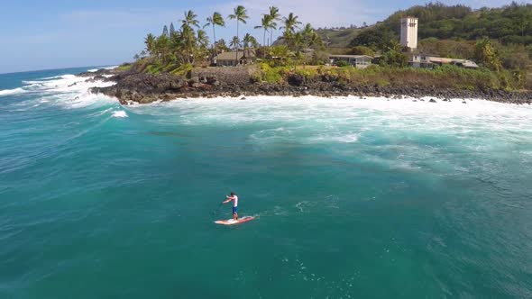 Aerial view of a man sup stand-up paddleboard surfing in Waimea, Hawaii