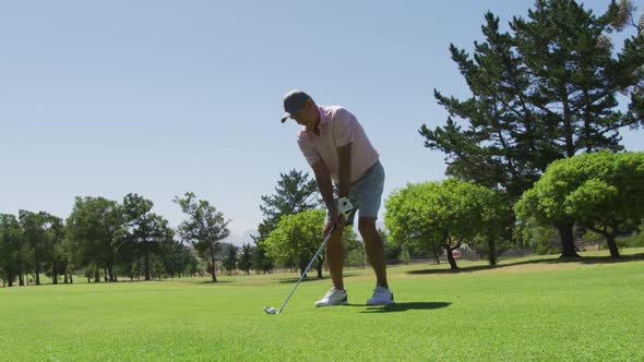 Caucasian senior man practicing golf at golf course on a bright sunny day