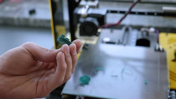 Closeup of a Male Engineer Demonstrates Plastic Models Printed on a 3D Printer