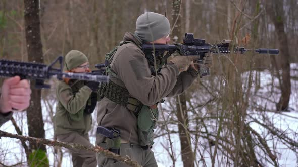 Side View Armed Soldiers Aiming Walking in Slow Motion in Winter Forest Outdoors