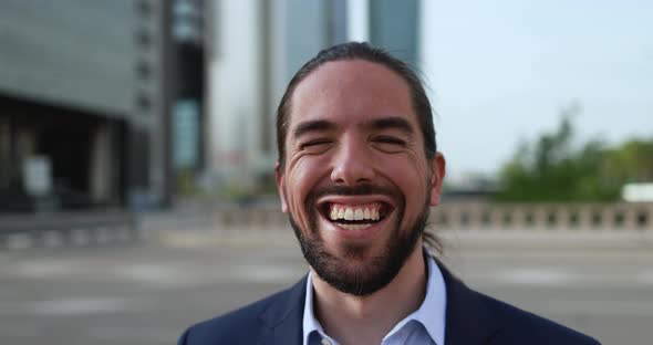 Happy latin business man working outside of the office with city in background