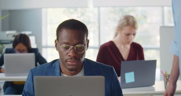 Experienced Executive Working with Young Businessman on Laptop in Modern Office