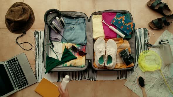 Top View Woman Unpack Suitcase for Summer Vacation