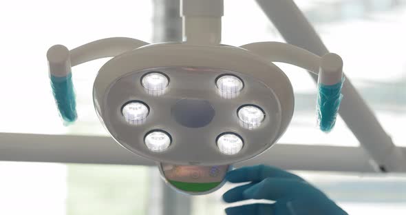 the Hand of a Dentist Doctor Turns on the Lamp of the Dental Chair in His Office Against the