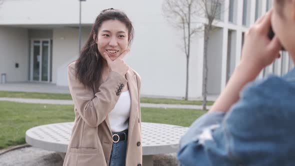 Young asian woman posing to the camera while the photographer girl taking a photo to her.