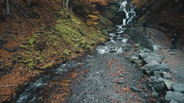 Foaming Waterfall Falls From Rocky Hill and Flows Along Path