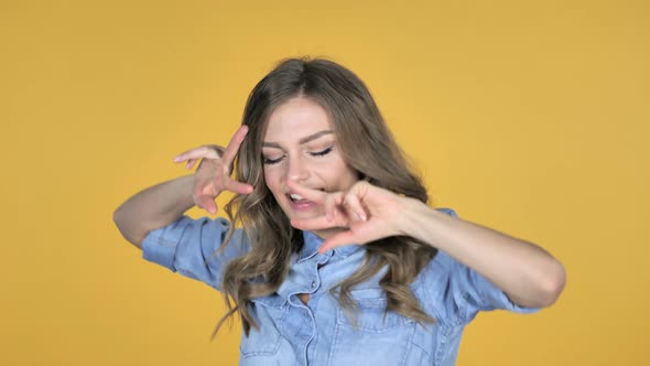 Pleased Smiling Young Girl Dancing Isolated on Yellow Background