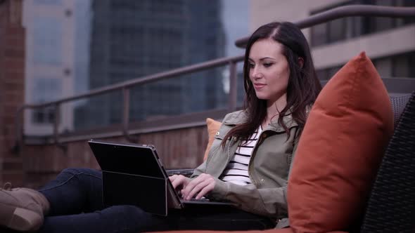 Up close view of woman relaxing on roof top typing on laptop