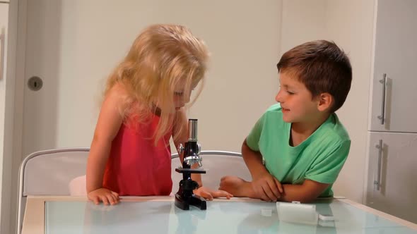 Boy is Sharing a Microscope with a Cute Girl in a Pink Top in a White Classroom