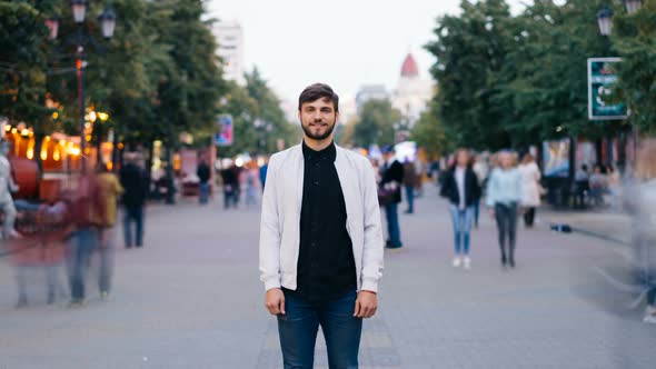 Zoom Out Time-lapse of Confident Young Man Looking at Camera Standing in City Center in Pedestrian